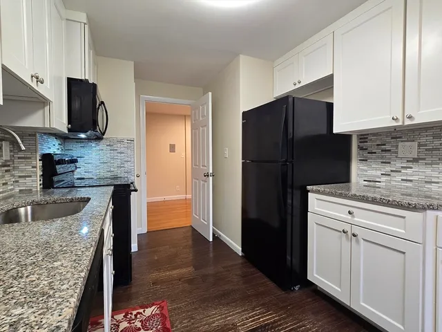 a kitchen with granite countertop wooden cabinets a refrigerator and a sink