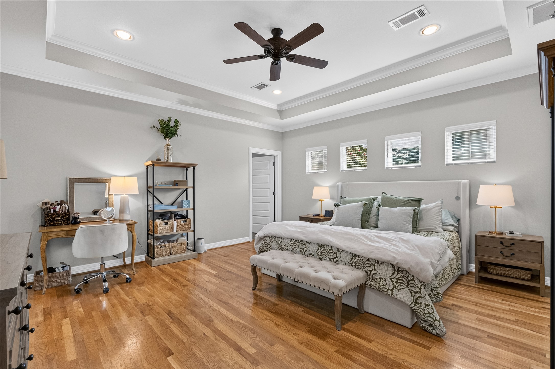 1722 Chippendale Road Houston, TX 77018 - Photo 17 of 41 Spacious and elegant primary bedroom featuring hardwood floors, a tray ceiling with recessed lighting, and a ceiling fan. Natural light streams through multiple windows, creating a bright and inviting atmosphere.