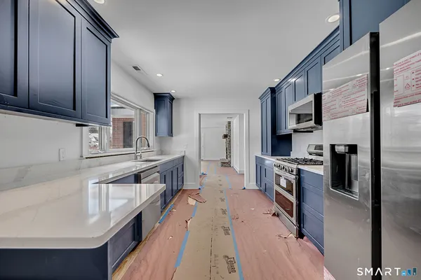 a kitchen with granite countertop a sink a counter top space stainless steel appliances and cabinets