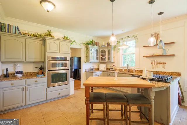 a kitchen with stainless steel appliances granite countertop a stove a sink and white cabinets with wooden floor
