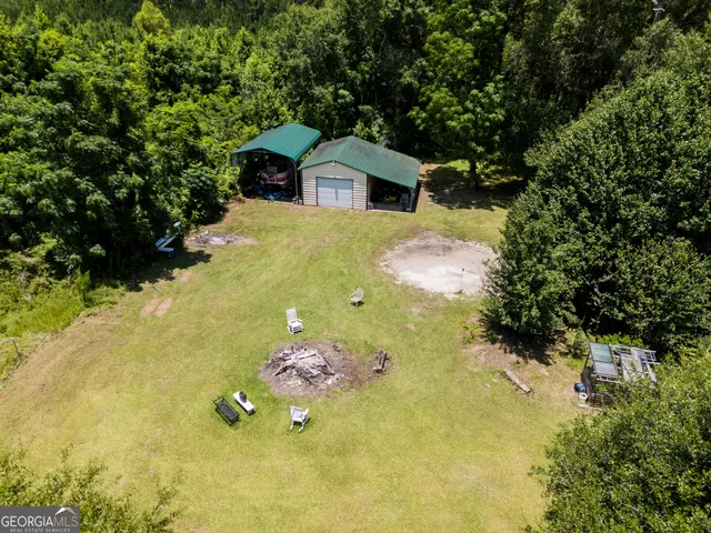 an aerial view of residential house with outdoor space and trees all around