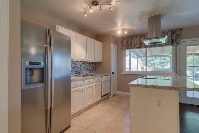 a large kitchen with stainless steel appliances kitchen island granite countertop a refrigerator and a sink