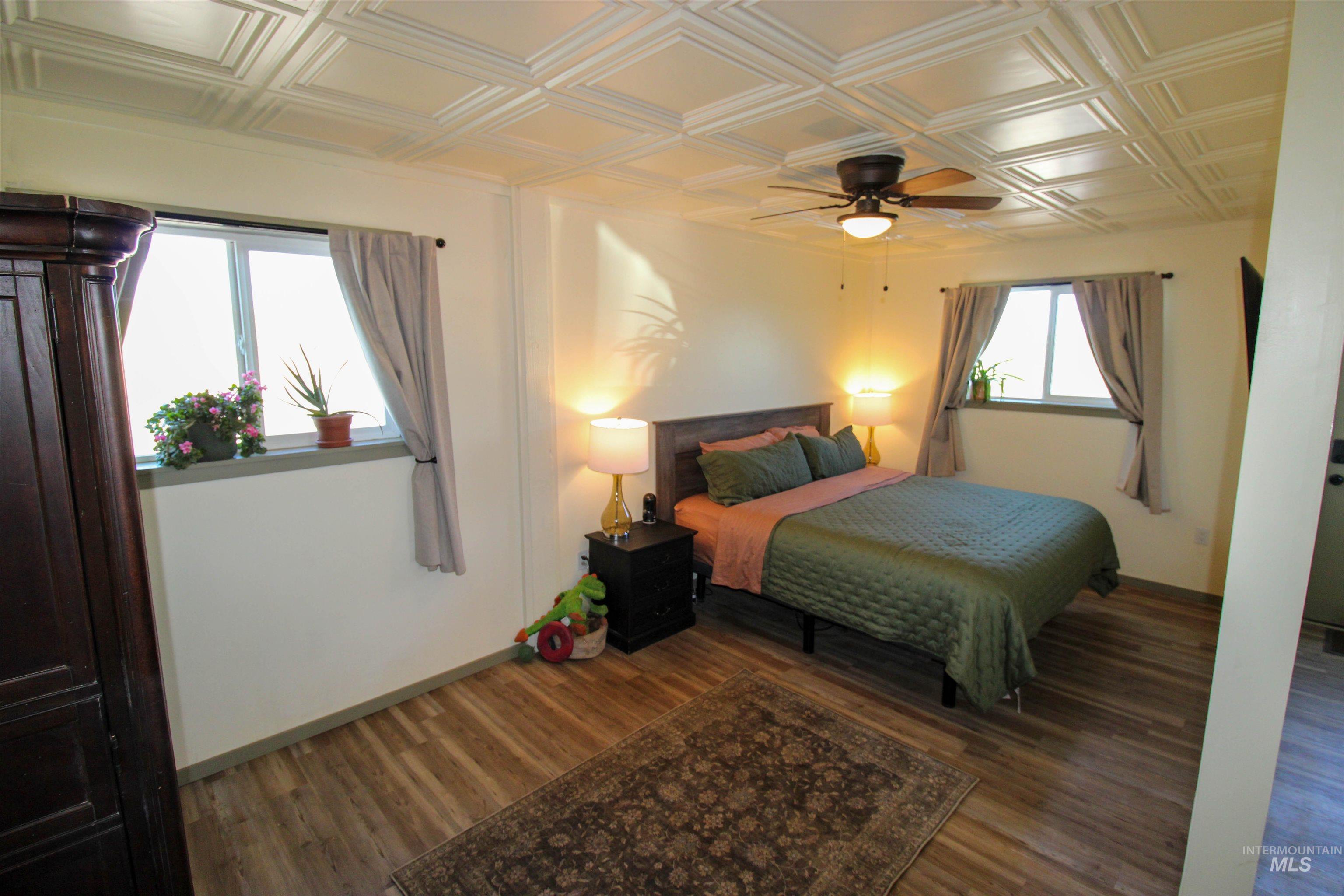 1254 Stuart Road Orofino, ID 83544 - Photo 14 of 48 Room featuring a decorative coffered ceiling with a ceiling fan, two windows with drapery rods, and wood-finish flooring