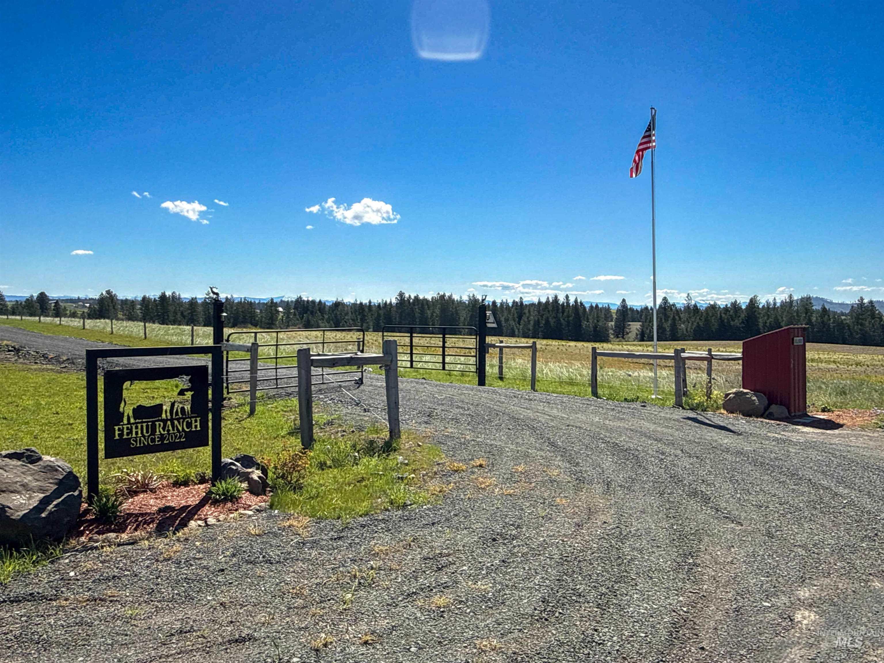 1254 Stuart Road Orofino, ID 83544 - Photo 2 of 48 Gravel driveway entrance featuring a custom metal ranch sign, a flag pole, and a red utility box