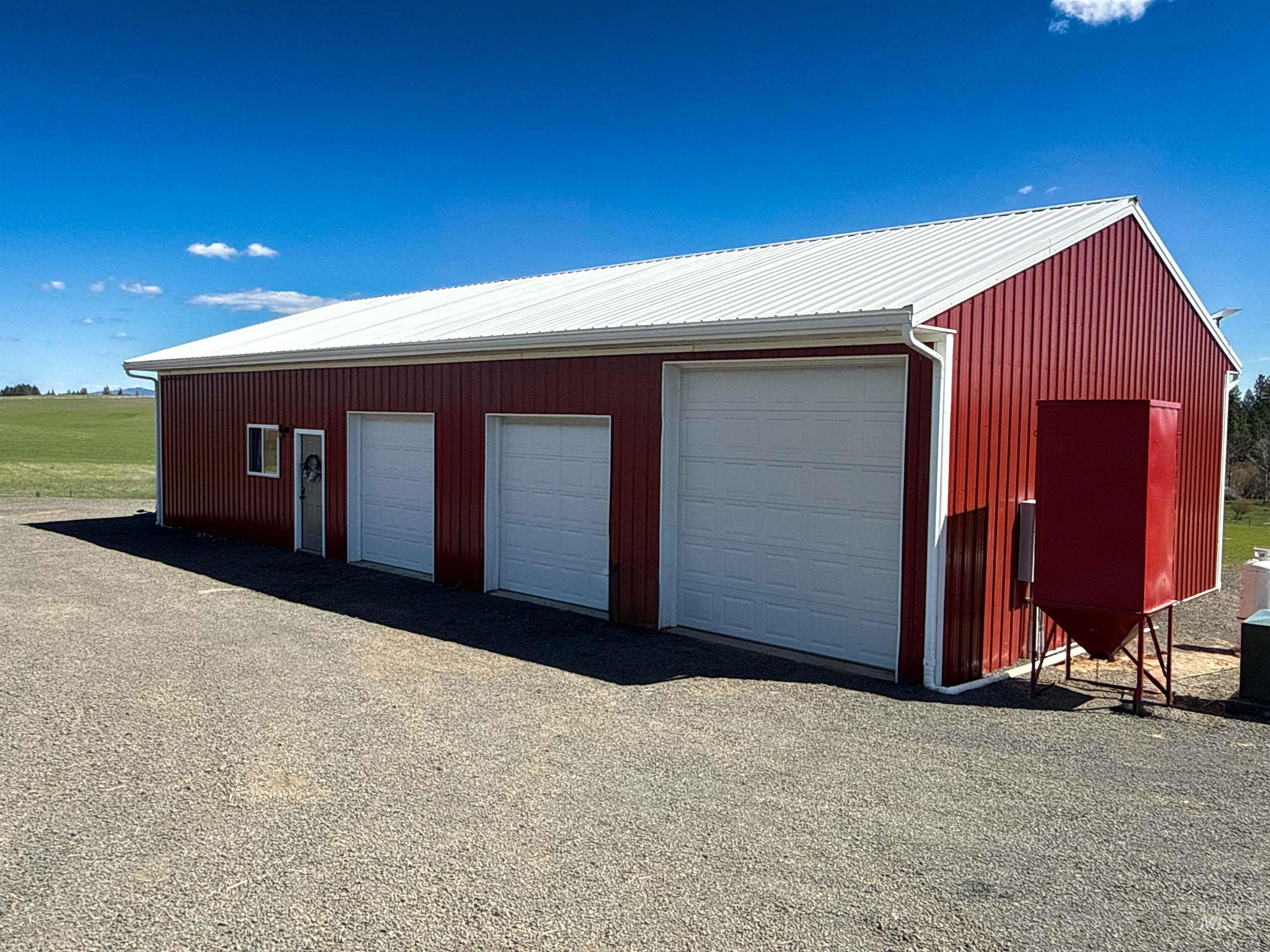 1254 Stuart Road Orofino, ID 83544 - Photo 4 of 48 Red metal-sided structure featuring a white metal roof, three garage doors, and a pedestrian entry door