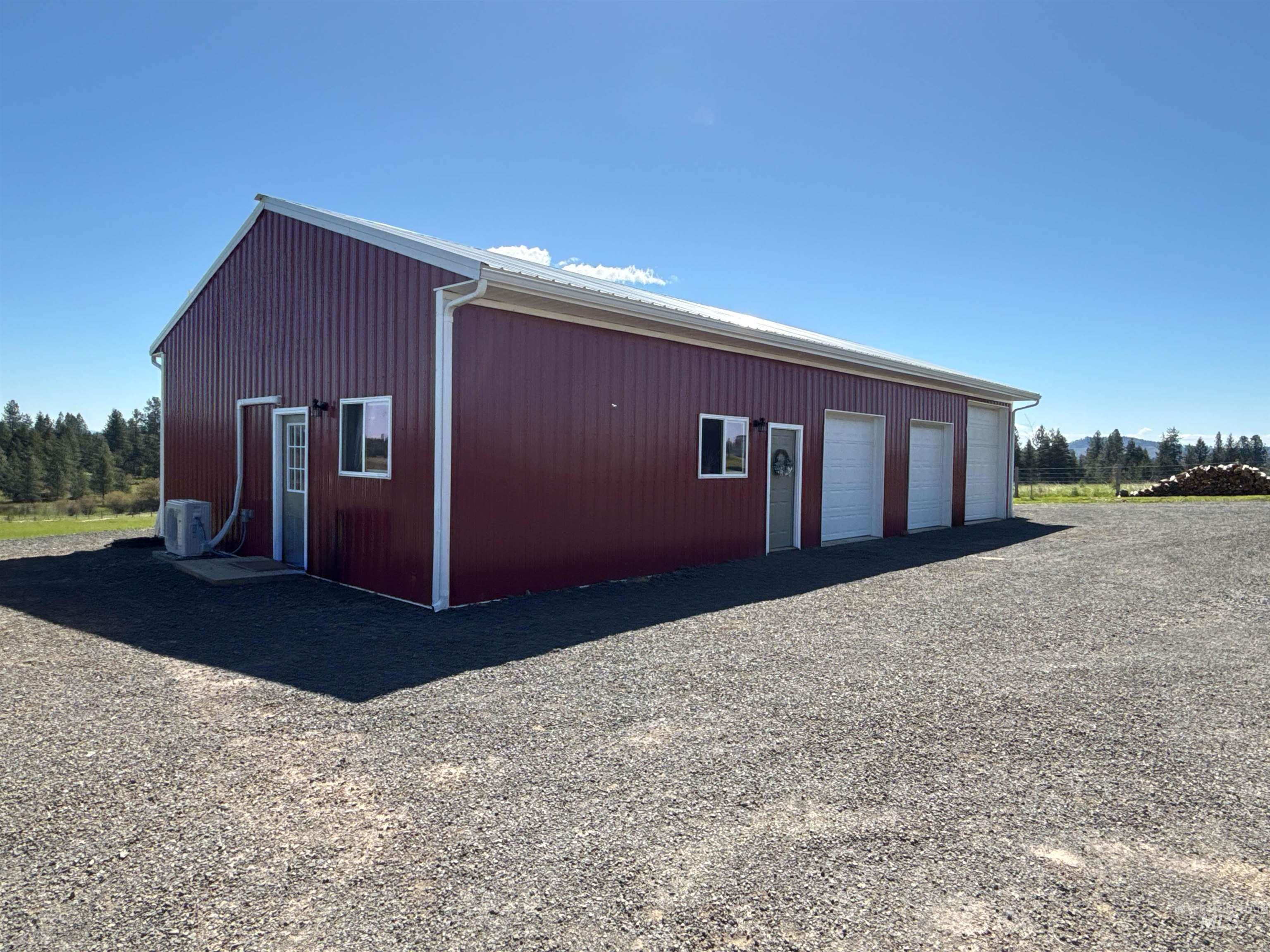 1254 Stuart Road Orofino, ID 83544 - Photo 5 of 48 Red metal-sided building featuring a white trim, multiple garage doors, and a gravel driveway