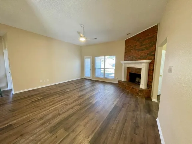 a view of empty room with wooden floor and fireplace