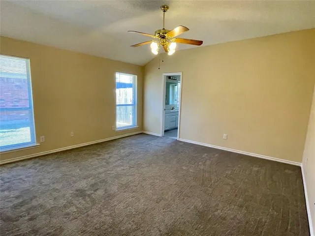 an empty room with a chandelier fan and a window