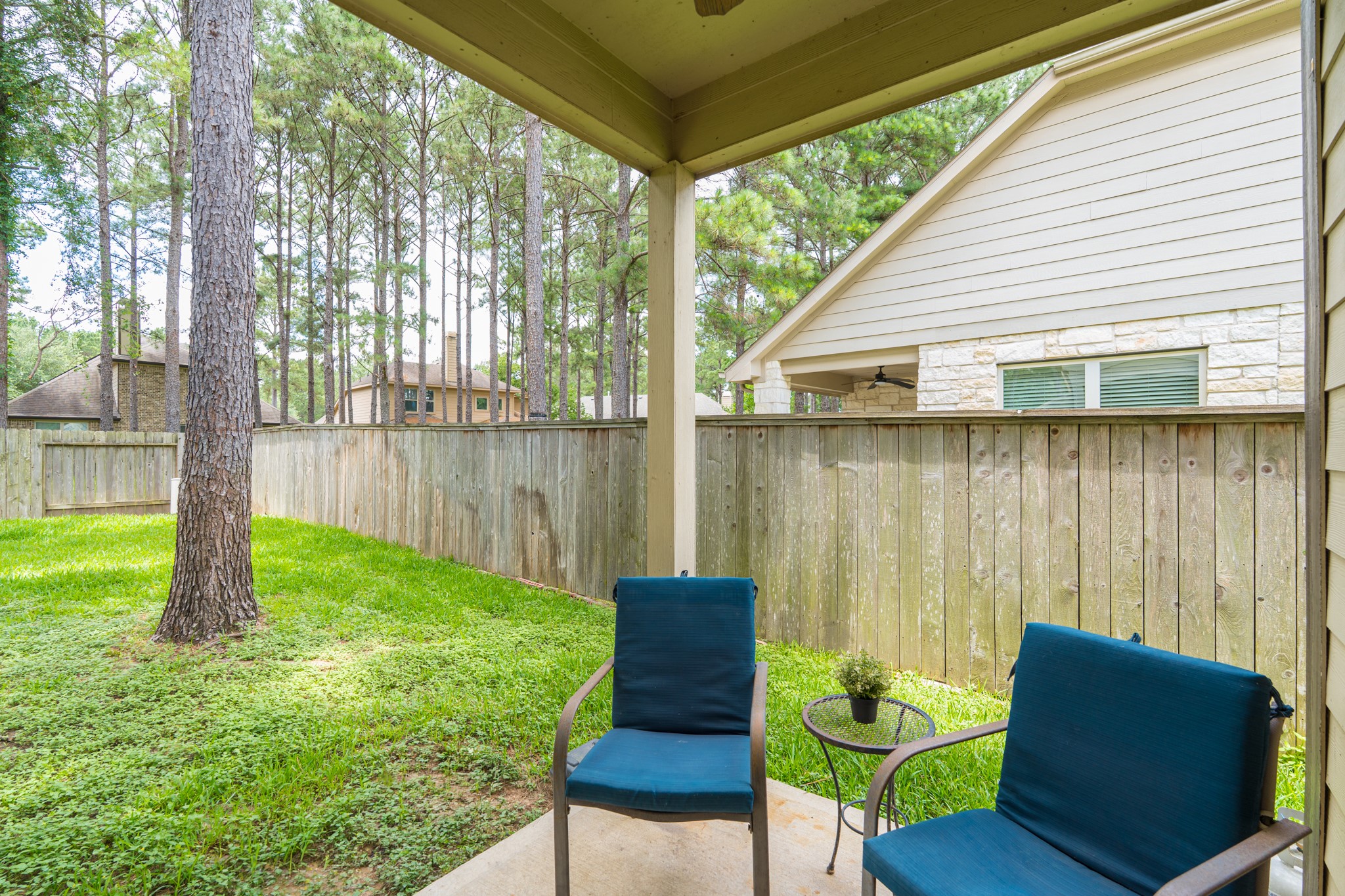 79 West Jagged Ridge Circle Spring, TX 77389 - Photo 41 of 50 Relax and unwind on this covered backyard patio, complete with comfortable seating and a peaceful view of the wood-fenced yard surrounded by towering pine trees. It's the perfect spot for morning coffee, evening relaxation, or weekend entertaining.