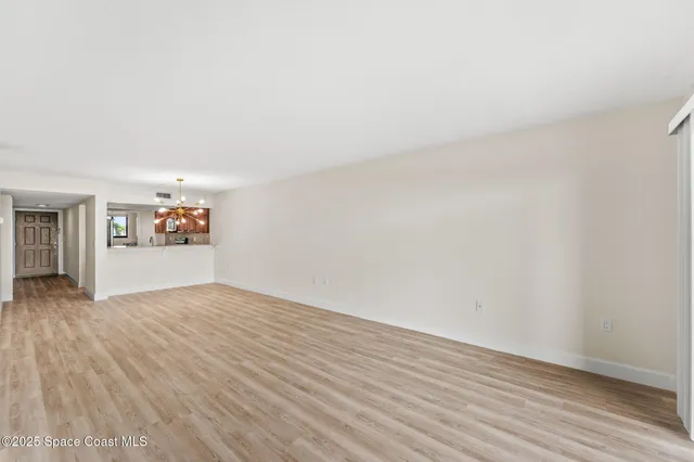 a view of a big room with wooden floor and a kitchen
