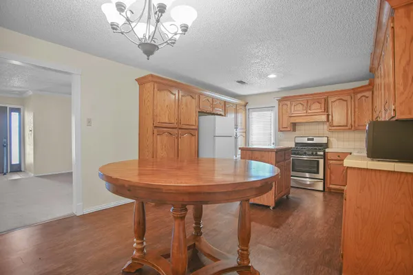 a kitchen with stainless steel appliances granite countertop a sink a stove a dining table and chairs with wooden floor