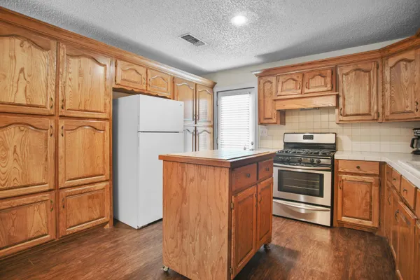 a kitchen with granite countertop a refrigerator stove top oven and sink