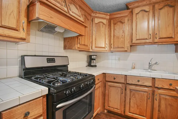 a kitchen with stainless steel appliances granite countertop a stove a sink dishwasher and cabinets with wooden floor