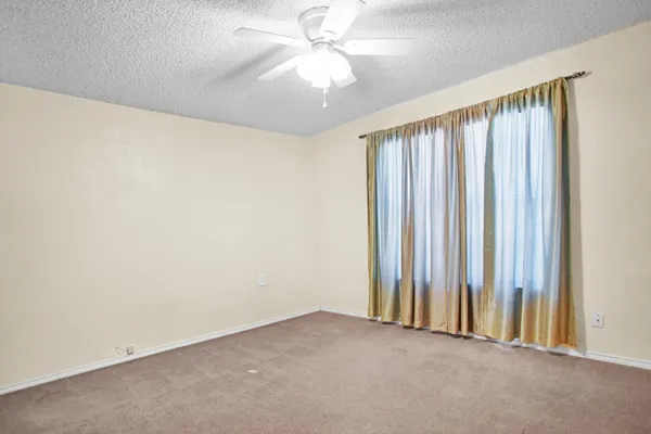 an empty room with windows and fan chandelier fan