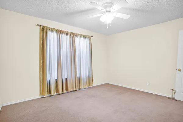 an empty room with a chandelier fan and windows