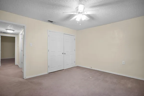 an empty room with a chandelier fan and a ceiling fan