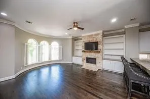 a view of a livingroom with a flat screen tv wooden floor and a ceiling fan