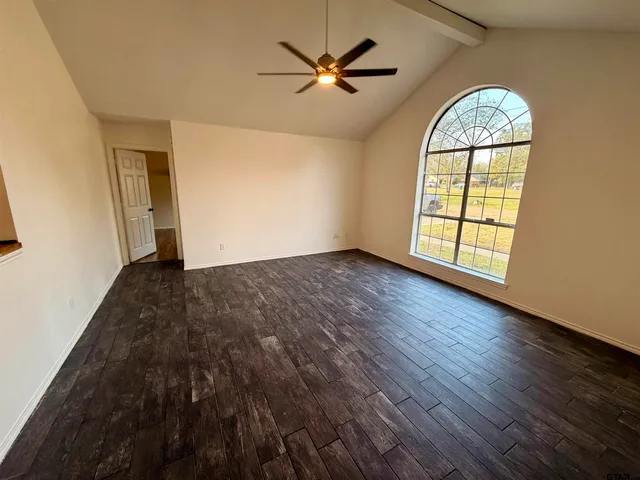 an empty room with wooden floor chandelier fan and windows