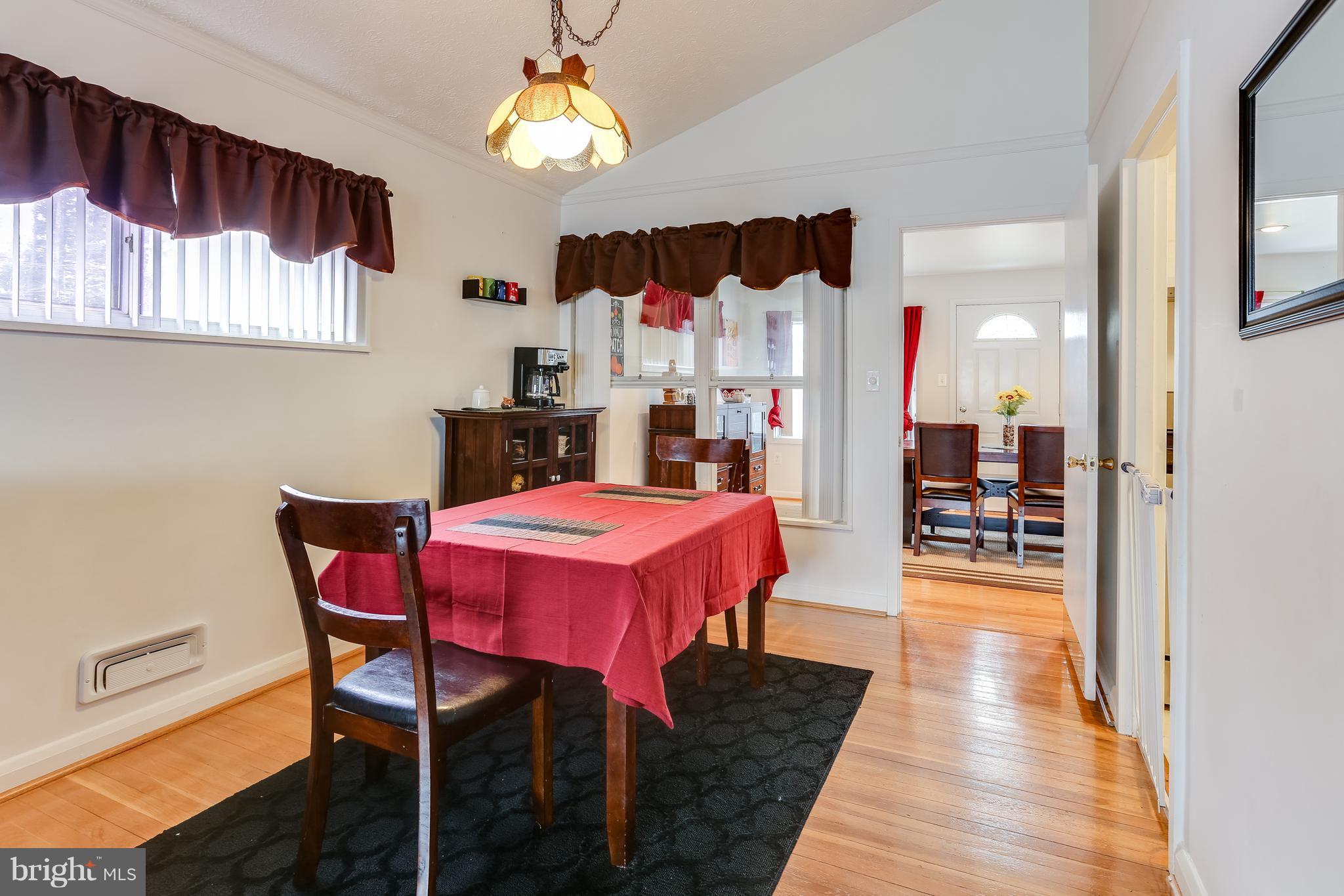 936 Vanderwood Road Baltimore, MD 21228 - Photo 6 of 27 a dining room with wooden floor a chandelier a wooden table and chairs
