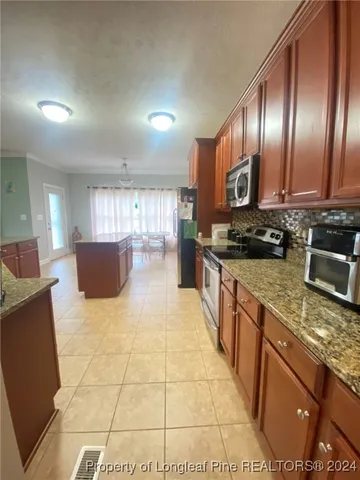 a kitchen with granite countertop a stove a sink and a wooden cabinets