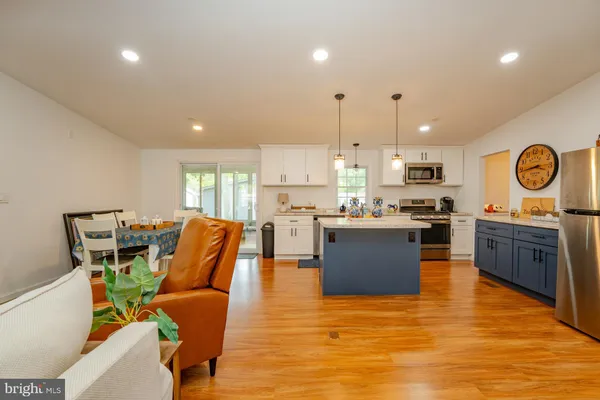 a large kitchen with stainless steel appliances granite countertop a stove top oven a sink dishwasher and white cabinets with wooden floor