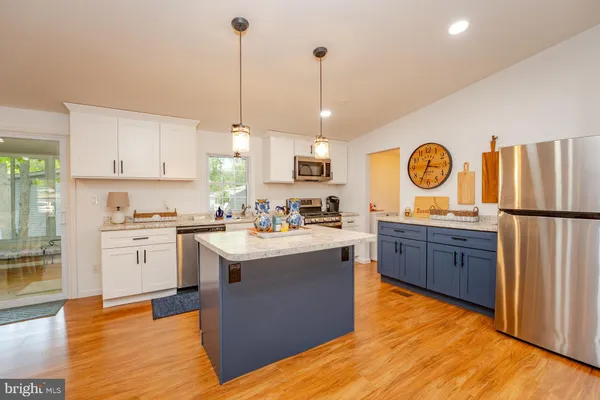 a kitchen with kitchen island granite countertop a sink a stove oven a counter space and cabinets