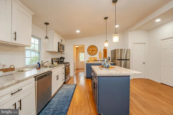 a large kitchen with stainless steel appliances granite countertop a large center island and a wooden floors