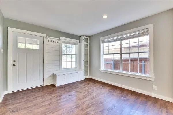 a view of an empty room with wooden floor and a window
