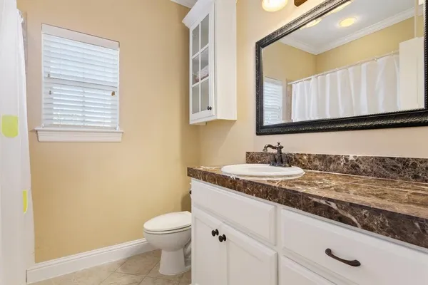 a bathroom with a granite countertop sink toilet and mirror