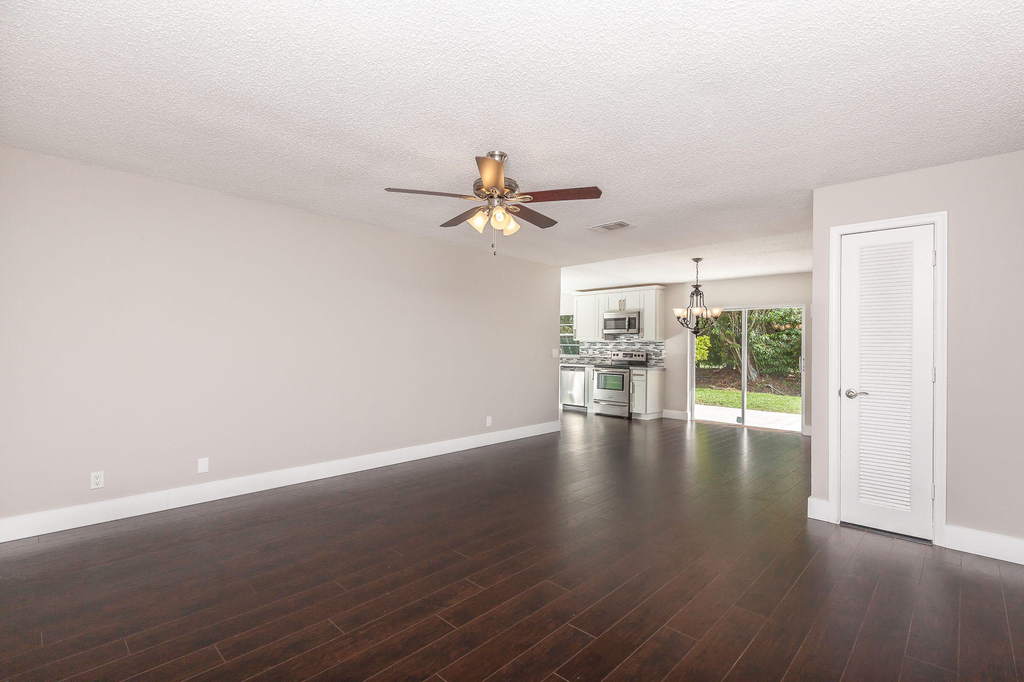 9868 Liberty Road Boca Raton, FL 33434 - Photo 4 of 22 a view of a livingroom with wooden floor a ceiling fan and windows