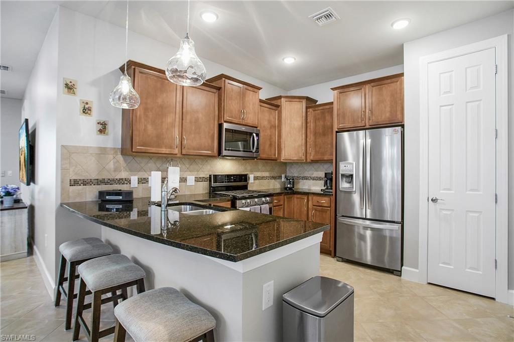 7674 Jacaranda Lane Naples, FL 34114 - Photo 12 of 45 a kitchen with stainless steel appliances granite countertop a refrigerator a stove top oven a sink and dishwasher