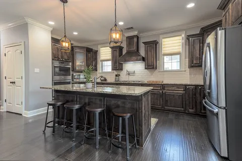 a kitchen with stainless steel appliances granite countertop a table chairs stove and refrigerator