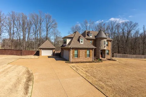 a front view of a house with a yard and covered with snow