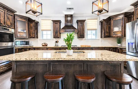 a kitchen with kitchen island granite countertop a sink a counter space appliances and cabinets