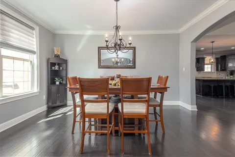 a dining room with furniture wooden floor a chandelier and a window