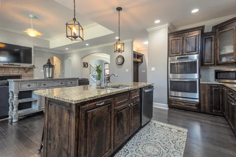 a kitchen with stainless steel appliances granite countertop a sink a stove and a wooden floors