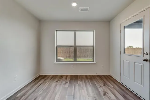 an empty room with wooden floor and windows