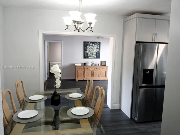 a dining room with wooden floor a chandelier a wooden table and chairs