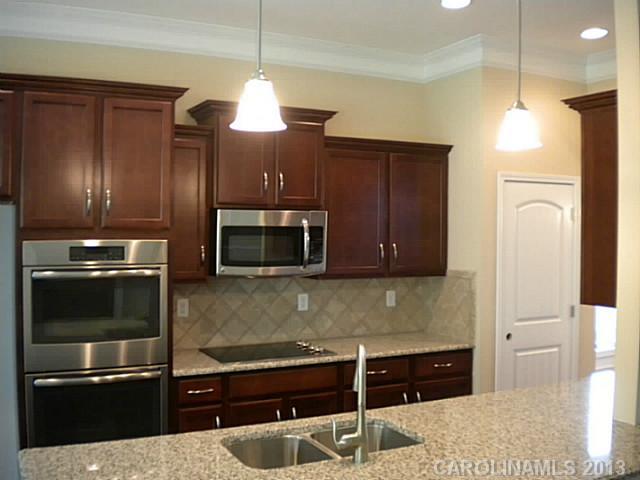 78014 Rillstone Drive, Unit 184 Lancaster, SC 29720 - Photo 8 of 16 a kitchen with granite countertop a refrigerator and a stove top oven
