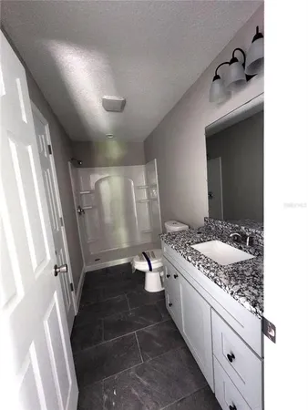 a bathroom with a granite countertop sink a toilet and shower
