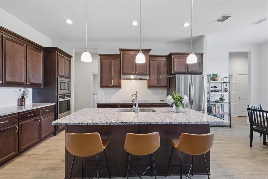 1607 Wagon Wheel Way Krum, TX 76249 - Photo 1 of 1 a kitchen with granite countertop a table chairs a sink and cabinets