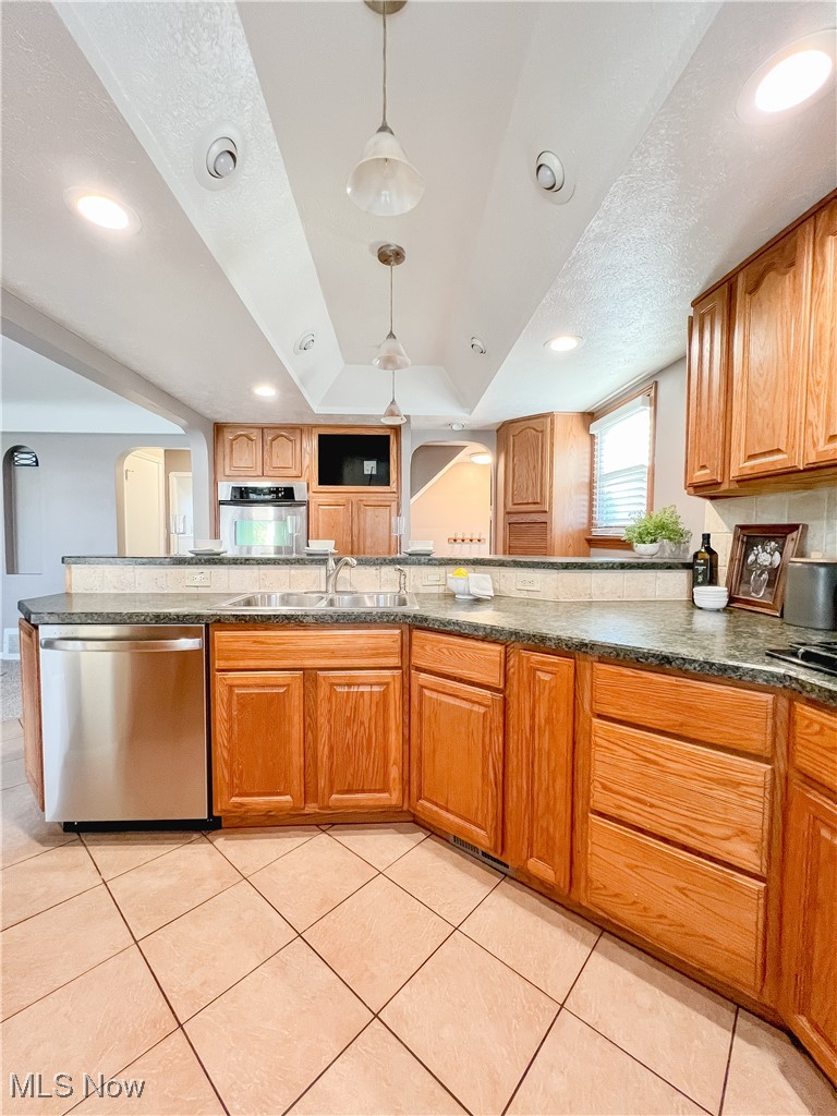 6403 Kenneth Avenue Parma, OH 44129 - Photo 6 of 20 Kitchen featuring arched walkways, stainless steel appliances, light tile patterned floors, hanging light fixtures, and wood cabinets