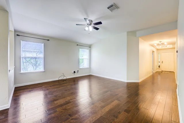 a view of an empty room with wooden floor and a window
