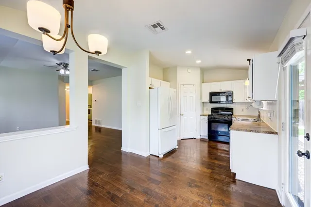 a view of kitchen with stainless steel appliances kitchen island refrigerator stove and wooden floor