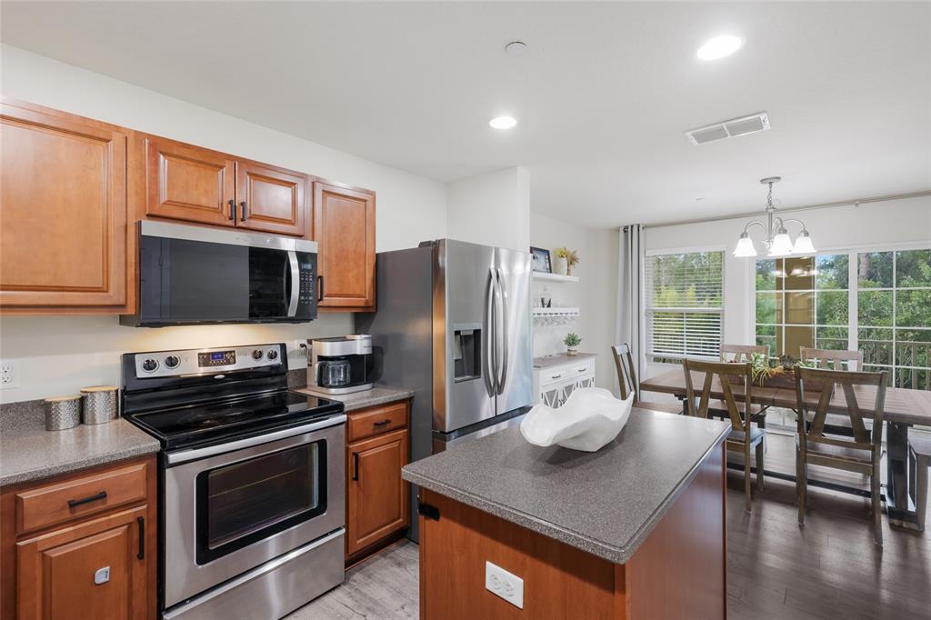 8907 White Sage Loop Lakewood Ranch, FL 34202 - Photo 8 of 33 a kitchen with stainless steel appliances a stove a sink a microwave a refrigerator a stove a dining table and chairs