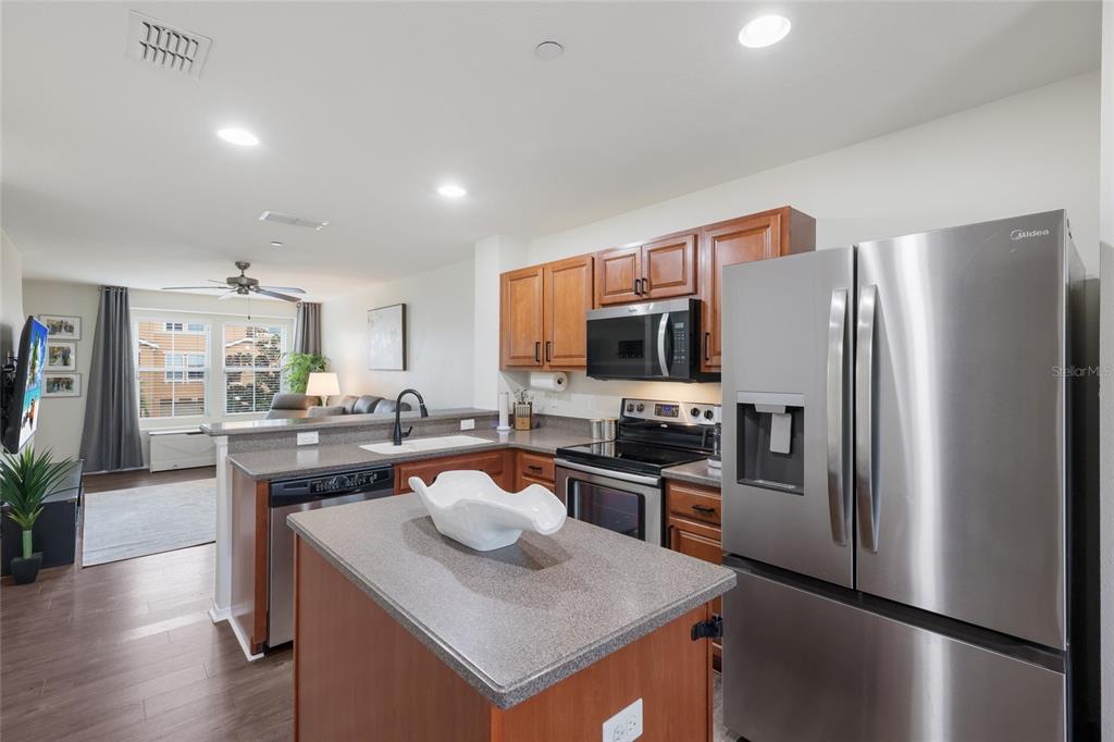 8907 White Sage Loop Lakewood Ranch, FL 34202 - Photo 9 of 33 a kitchen with stainless steel appliances granite countertop a refrigerator a stove top oven a sink dishwasher and white cabinets with wooden floor