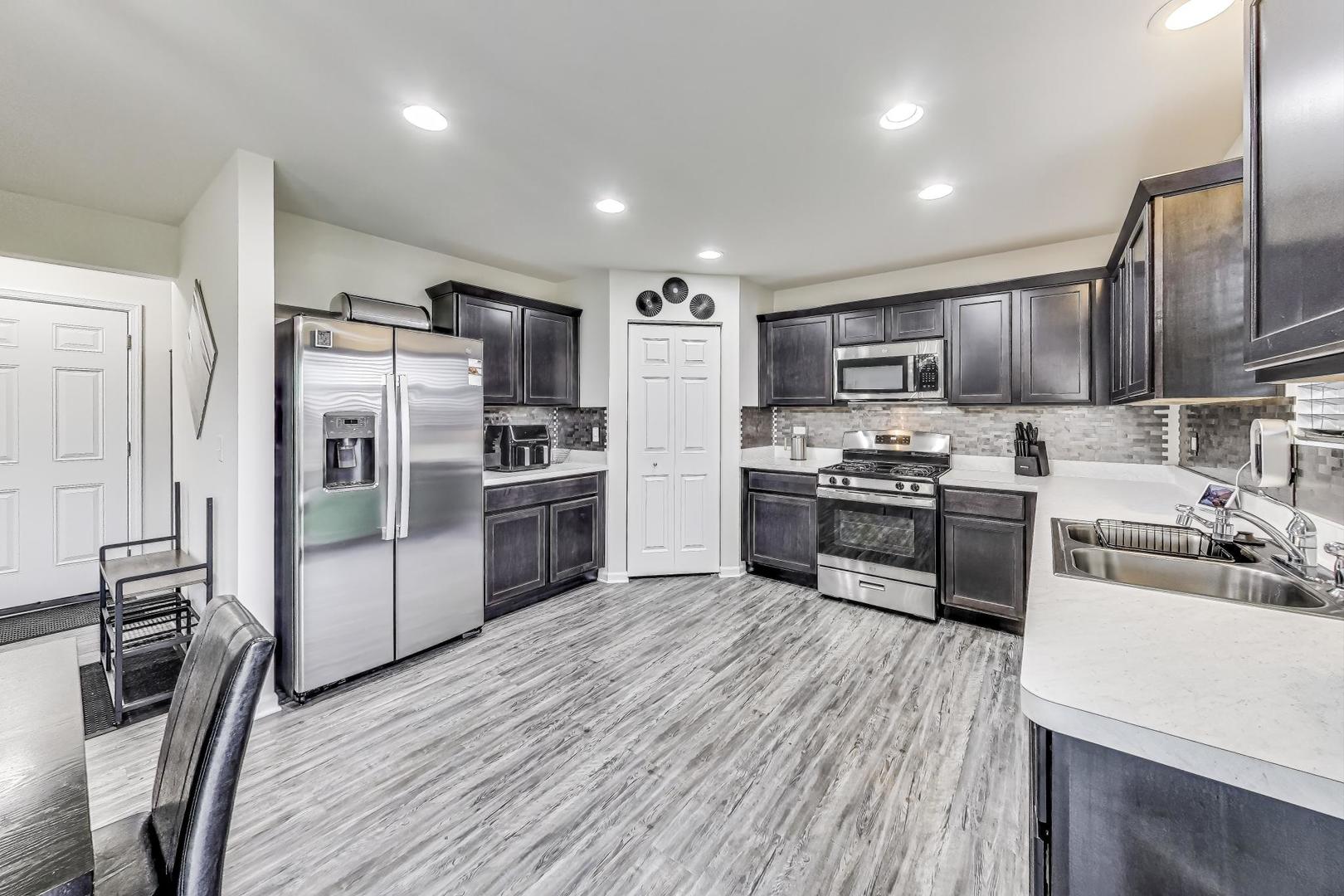 1014 Sharp Drive Plano, IL 60545 - Photo 14 of 52 a kitchen with stainless steel appliances wooden floor sink and wooden cabinets