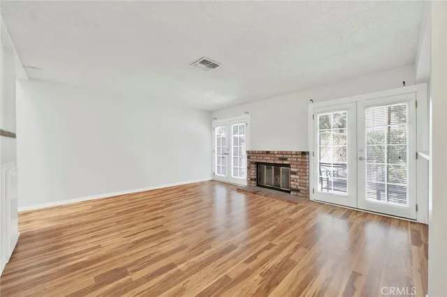 a view of empty room with wooden floor and fireplace