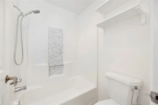 a bathroom with a granite countertop bathtub shower and toilet