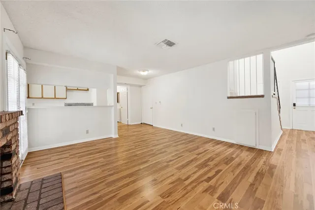 a view of empty room with wooden floor and window
